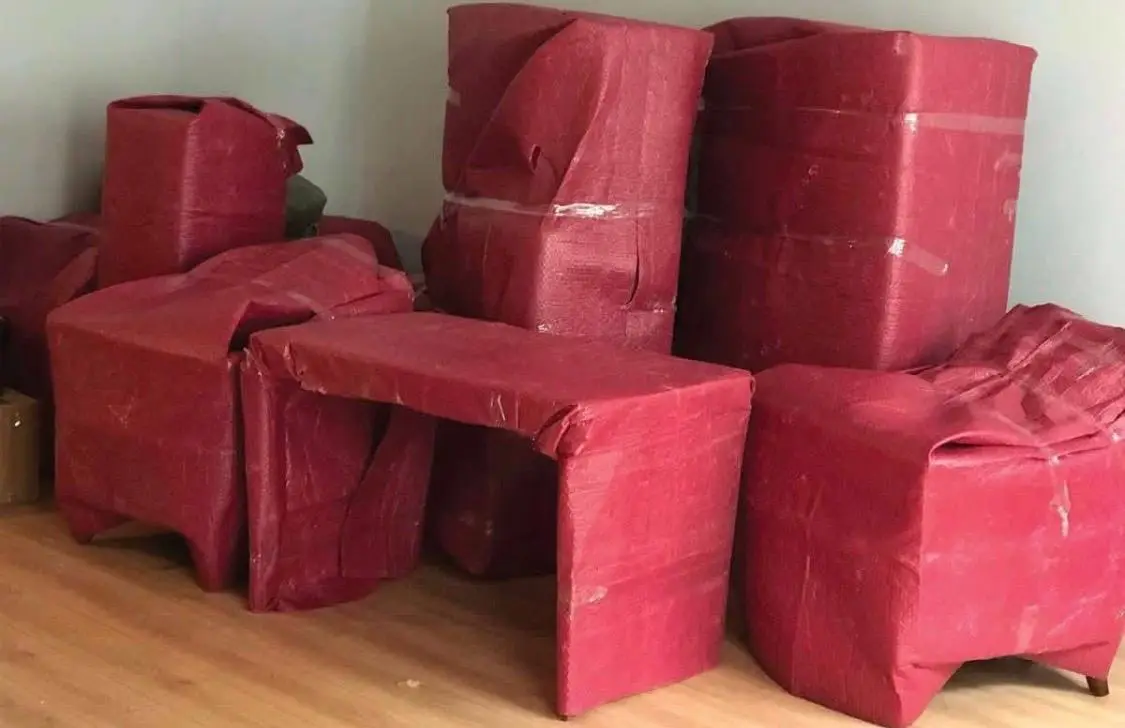 Küçükçekmece nakliyat: kırmızı koruyucuyla paketlenmiş masa ve koltuklar